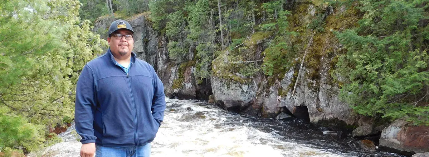 Guy Anahkwet Reiter stands near the Menominee River, which is sacred to the Menominee Tribe.